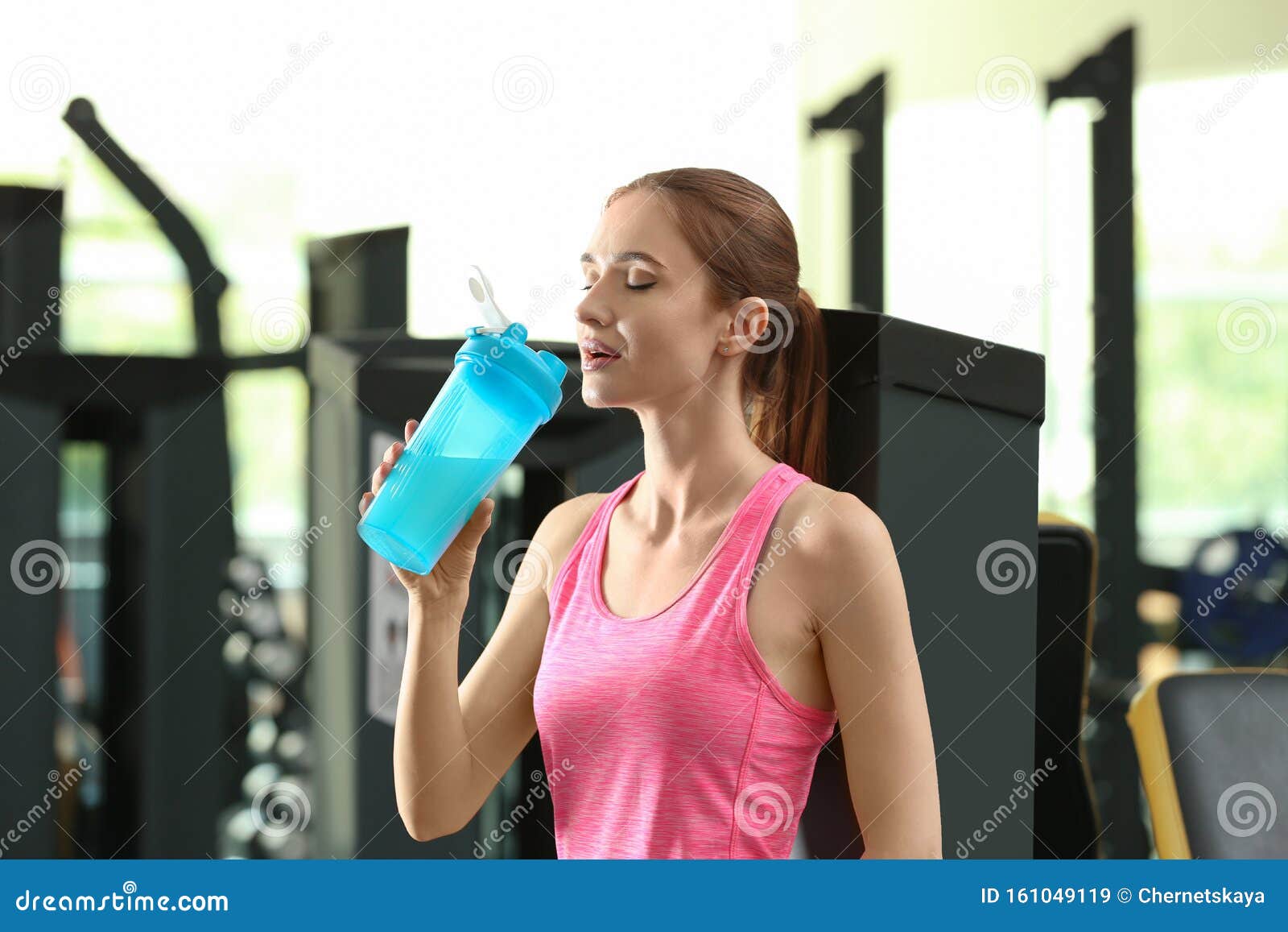 Ung kvinna som dricker proteinshake efter gympass